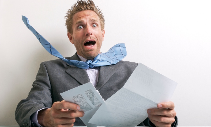 IRS audits to increase photo concept shows businessman in a suit with his tie blown back when opening an audit letter.