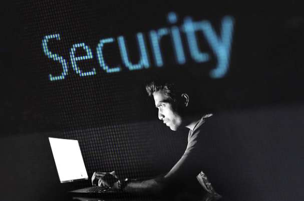 Fraud awareness concept photo of a man hacking a computer with security in bold text over his head.